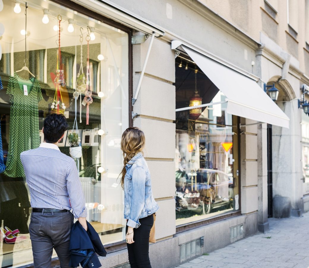 Couple looking at clothes displayed on store window