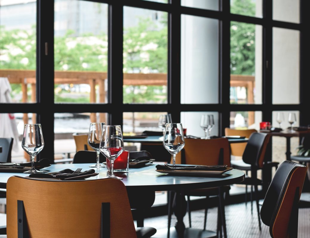 Empty tables set at restaurant with large wall to wall windows ready for guests