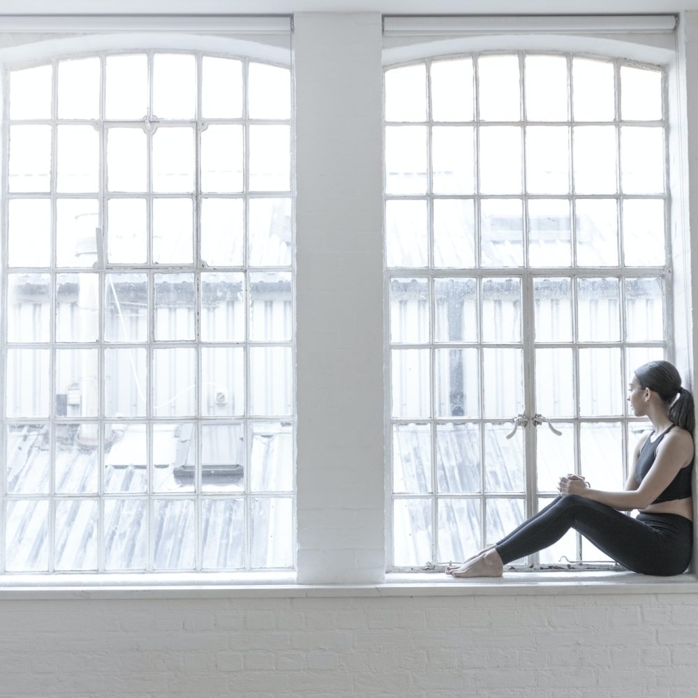 Woman sitting on windowsill looking out of window