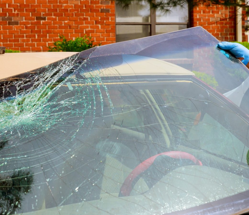 Workers remove crashed windshield of a car in auto oudoors service